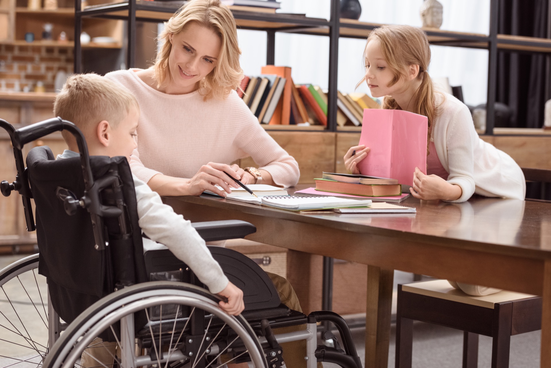 Young mom showing son in wheelchair a book